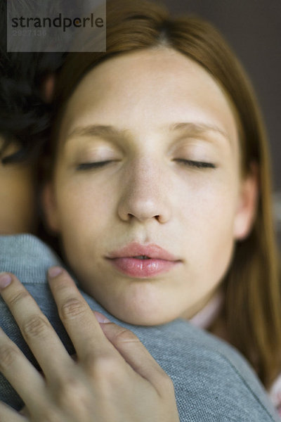 Junge Frau umarmt Mann  Augen geschlossen  Nahaufnahme