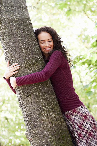 Junge Frau umarmt Baum