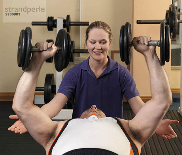 Mann trainiert mit Gewichten im Fitnessstudio