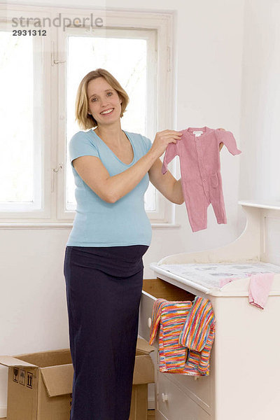 schwangere Frau bei der Auswahl der Babykleidung