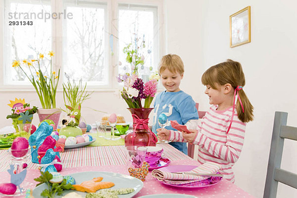 Mädchen und Junge bewundern Ostertafel