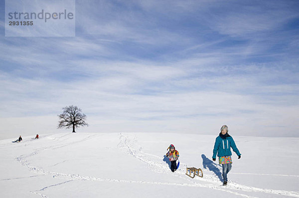 Junge und Mädchen mit Schlitten im Schnee