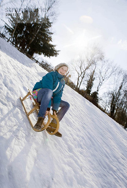 Mädchen beim Schlittenfahren im Schnee