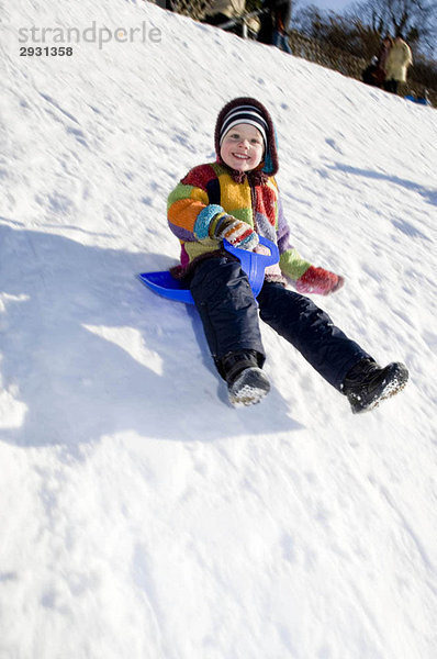 Junge auf einem Schlitten im Schnee