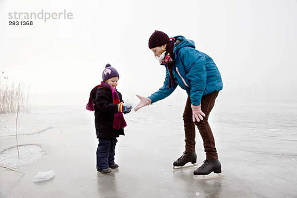 Mädchen und Junge eislaufen auf dem zugefrorenen See