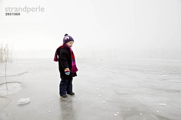 Junge auf gefrorenem See im Nebel