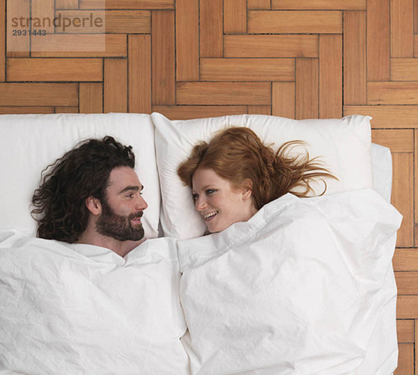 Paar im Bett liegend  lächelnd