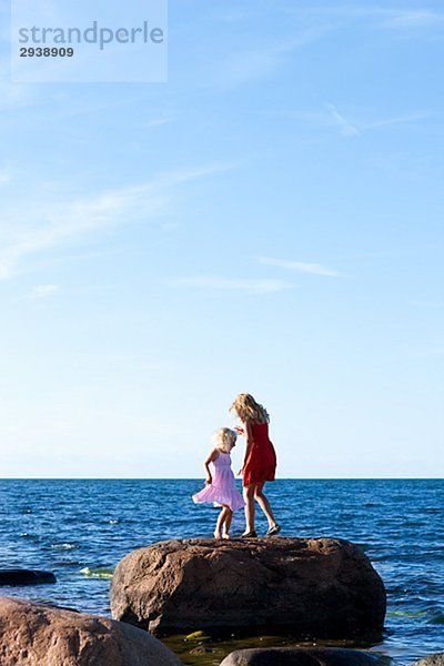 Zwei Schwestern auf einem Felsen am Meer Schweden.