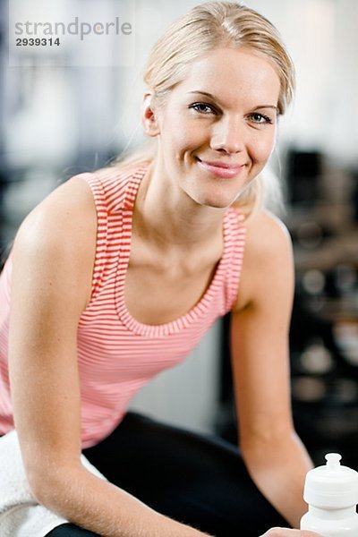 Eine Frau mit einer Flasche Wasser in einem Fitnessstudio Schweden.