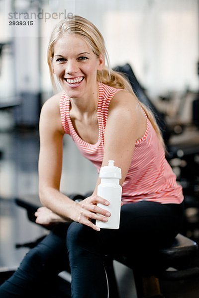 Eine Frau mit einer Flasche Wasser in einem Fitnessstudio Schweden.