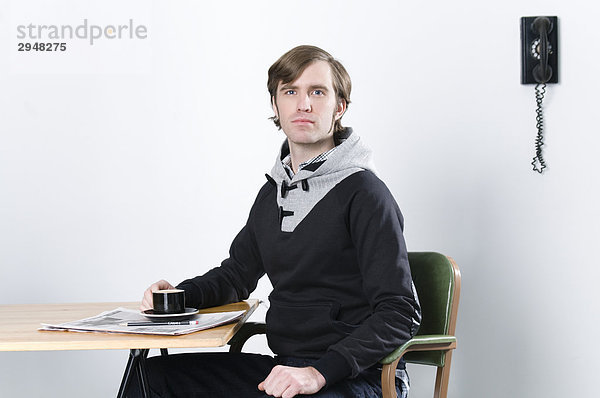 Porträt eines Mannes mit einem Kaffee an Schreibtisch sitzen