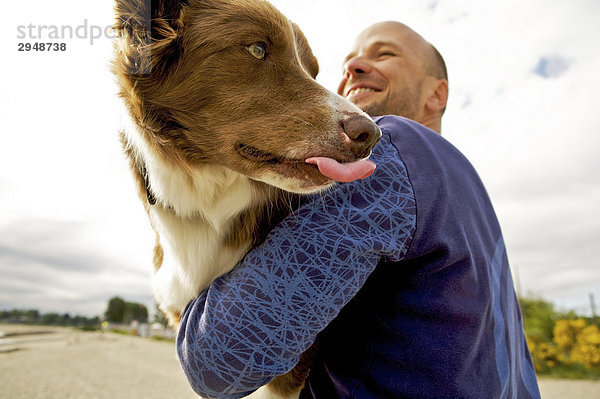 Mann umarmt seinen Hund  Jericho Beach  Vancouver  British Columbia