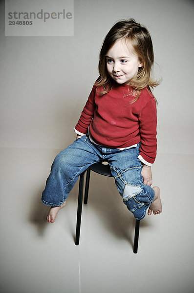 Little Girl with red Sweater und Jeans posiert auf einem Stuhl und Lächeln  Otterburn Park  Québec