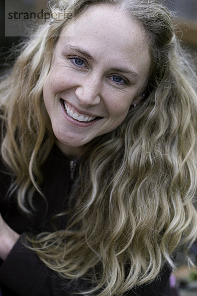Portrait einer Frau with long wellig Blondes Haar  lächelnd.