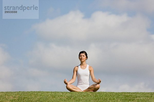 Young Woman sitting on Grass im Schneidersitz position