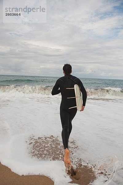 Mann zu Fuß ins Meer mit seinem Surfbrett
