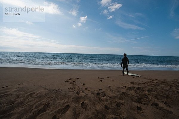 Junger Mann im Anzug stehen am Strand