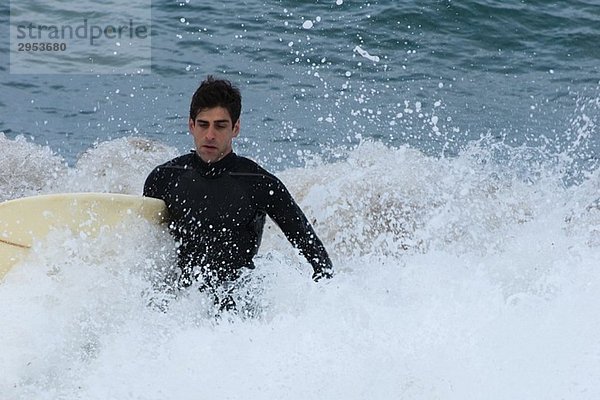 Junger Mann in das Meer mit seinem Surfbrett