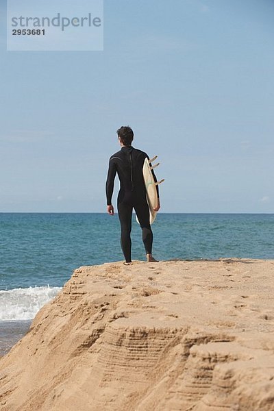 Surfer stehen auf Rock und Surfbrett unter seinem Arm hält