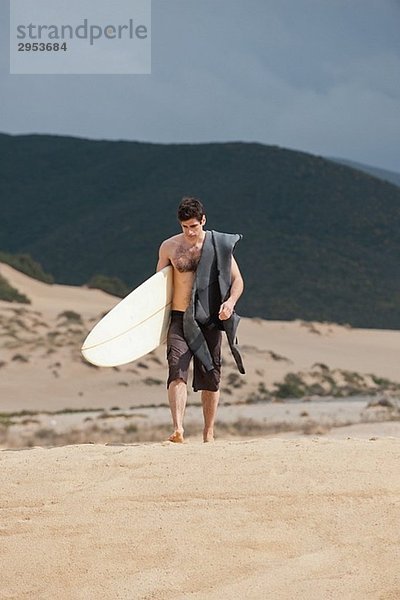 Surfer Surfboard hält und Wandern am Strand