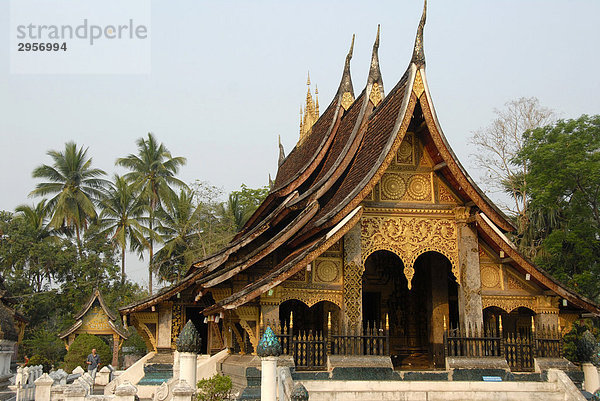 Nationalsymbol alter buddhistischer Tempel mit geschwungenem Dach vor Palmen  Kloster Wat Xieng Thong  Luang Prabang  Laos  Südostasien