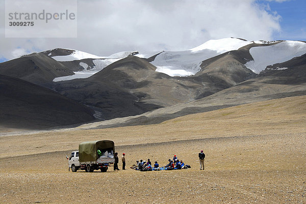 Trekkinggruppe macht Rast mit LKW auf weiter Flur vor schneebedeckten Bergen auf dem Nam-La Pass 5250 m Everest Gebiet Tibet China