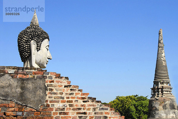 Kopf einer Buddhafigur gegenüber vom Tempelturm Wat Yai Chai Mongkol Ayutthaya Thailand