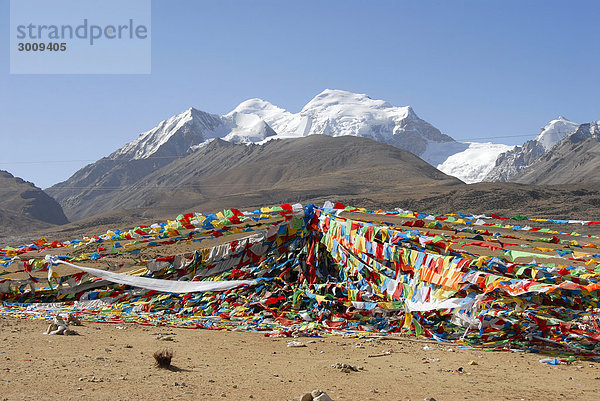 Bunte Gebetsfahnen wehen vor eisbedecktem Nyenchen Tanglha (7162 m) Tibet China