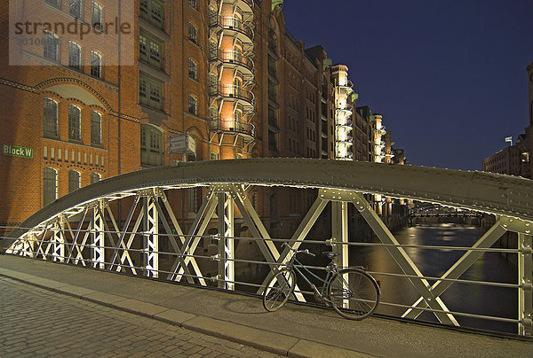 Ein Fahrrad lehnt an einer beleuchteten Brücke in der Hamburger Speicherstadt  Hamburg  Deutschland