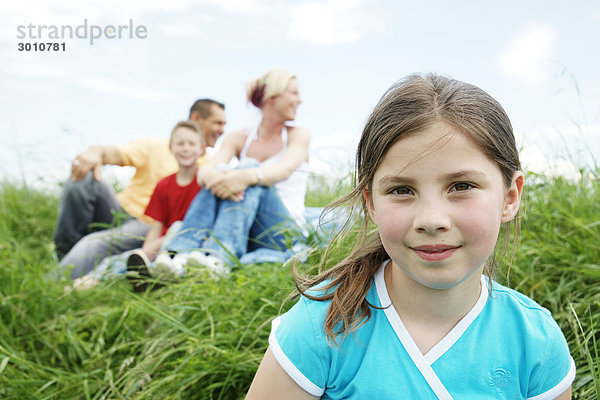 Familie mit zwei Kindern sitzt im Gras