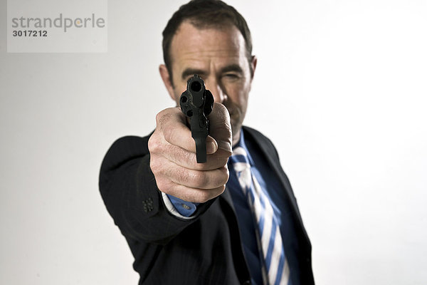 Geschäftsmann zielt mit einer Waffe auf die Kamera  Frontal