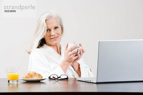 Mittelalterliche Frau beim Frühstücken mit dem Laptop