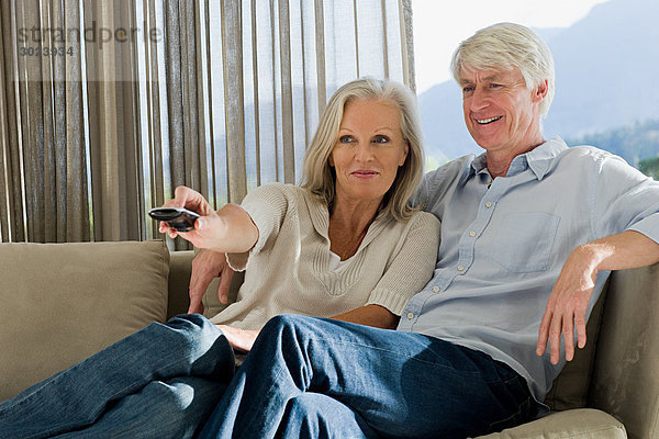 Mittelalterliches Paar  das zusammen auf der Couch sitzt und fernsieht.