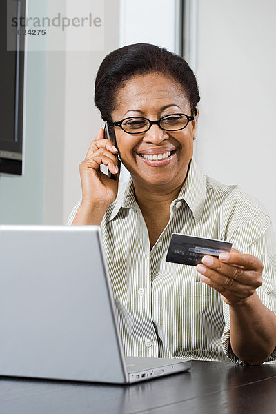 Frau mit Laptop-Handy und Kreditkarte