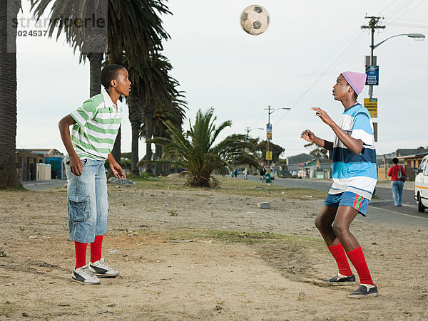 Jungen spielen Fußball auf der Straße