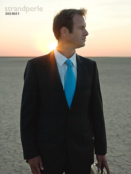 Geschäftsmann bei Sonnenuntergang in der Wüste