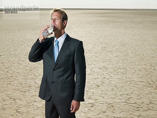 Geschäftsmann Trinkwasser in der Wüste