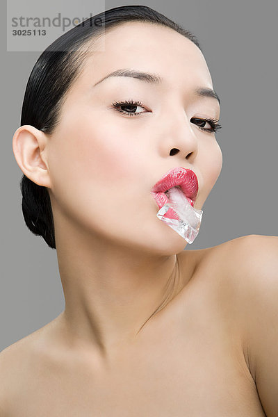 Frau mit pfeilförmigem Eiswürfel im Mund