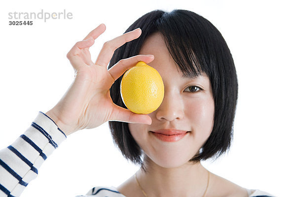 Frau hält sich eine Zitrone ans Auge