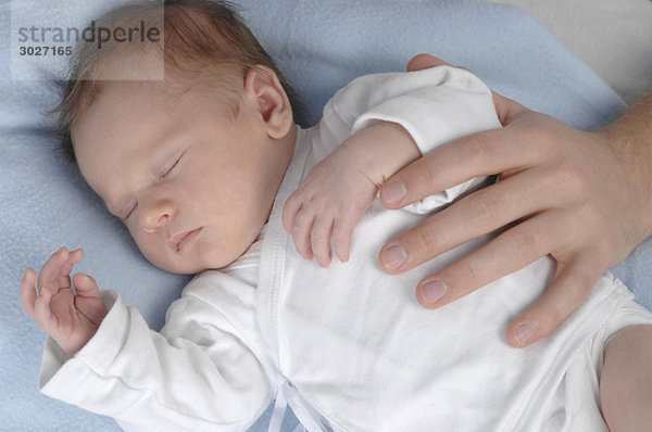 Baby Junge (3 Wochen) schlafend  von erwachsener Hand berührt  Nahaufnahme