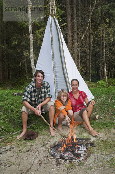 Austria  Salzburger Land  Family sitting at campfire