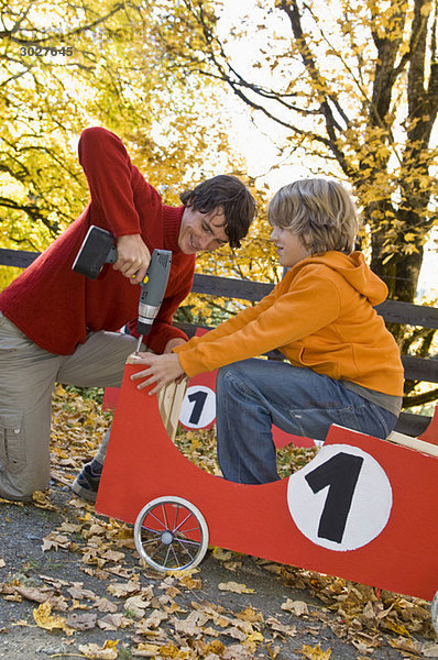 Austria  Salzburger Land  Young man fixing soapbox car  boy (12-13) assisting