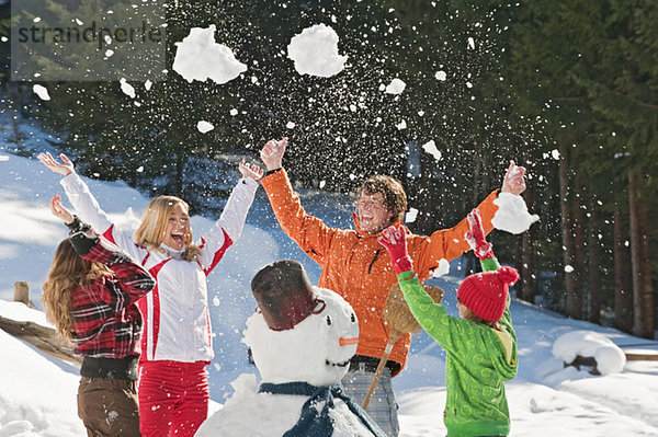Österreich  Salzburger Land  Altenmarkt  Familie beim Schneemann  Schnee in die Luft werfen  Lachen  Porträt