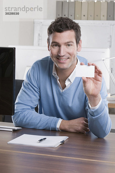 Geschäftsmann im Büro mit Visitenkarte  lächelnd  Portrait