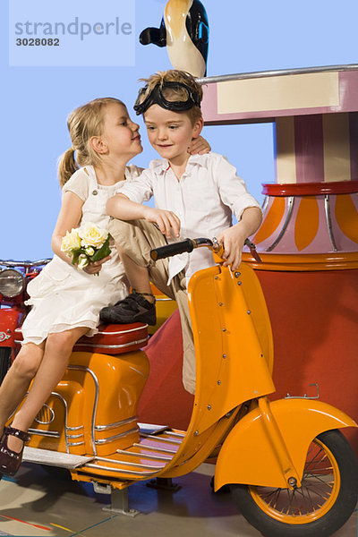 girl kissing boy (4-5)  sitting in carousel