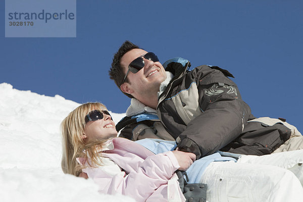 Deutschland  Bayern  Paar in Winterkleidung im Schnee liegend
