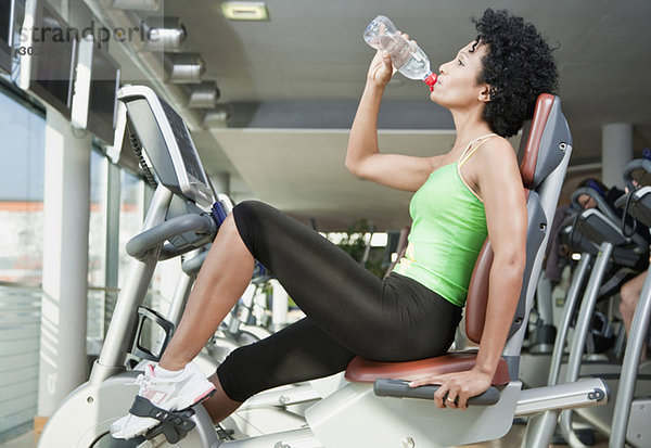 Frau trinkt Wasser im Fitnessstudio  Seitenansicht  Portrait