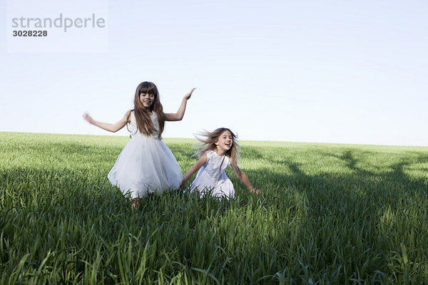 Zwei Mädchen (8-9) laufen im Feld  lachend  Portrait