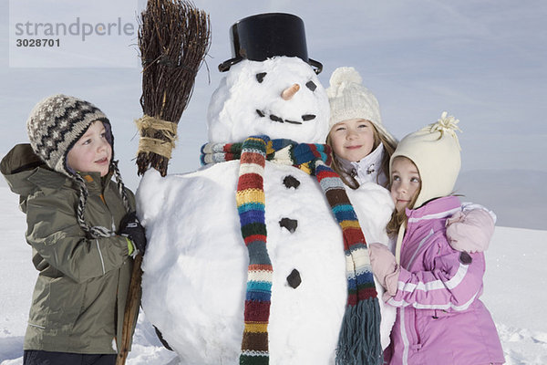 Deutschland  Bayern  München  Kinder (4-5) (8-9) neben Schneemann  Portrait