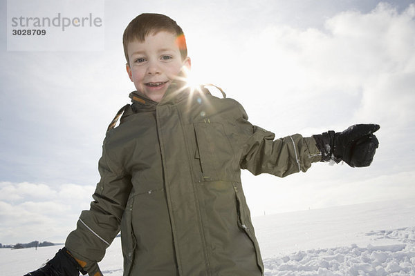 Junge (8-9) in verschneiter Landschaft  lächelnd  Portrait